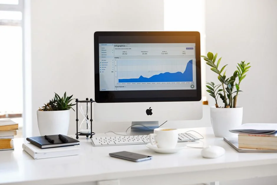 A modern workspace showing hands analyzing marketing data on a laptop and paper documents.